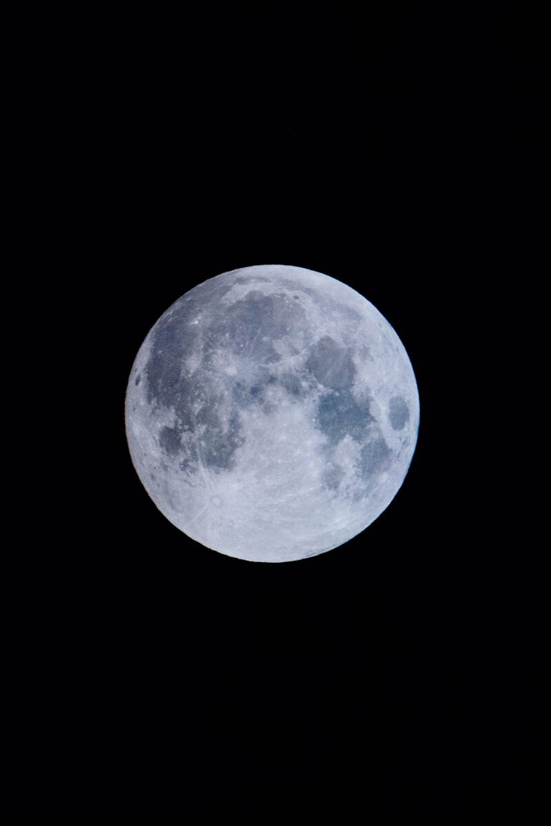 A full moon rising over a darkened sky
